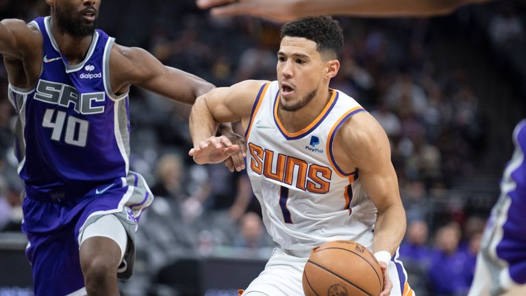 Phoenix Suns guard Devin Booker (1) drives to the basket as he is defended by Sacramento Kings forward Harrison Barnes (40) in the second half of an NBA basketball game in Sacramento, Calif., Sunday, March 20, 2022.  The Suns won 127-124.(AP Photo/Jos.. Luis Villegas)